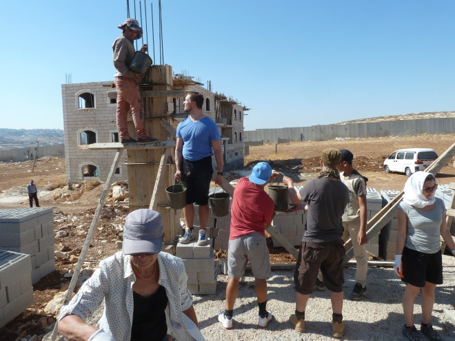 Die Schächte für die 9 Säulen werden mit Beton gefüllt: die Eimer mit dem Mörtel werden von Hand zu Hand weitergereicht.